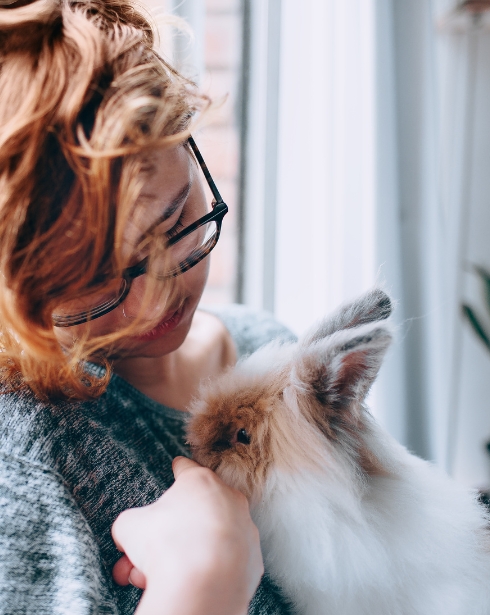 A Woman holding a fluffy brown and white rabbit